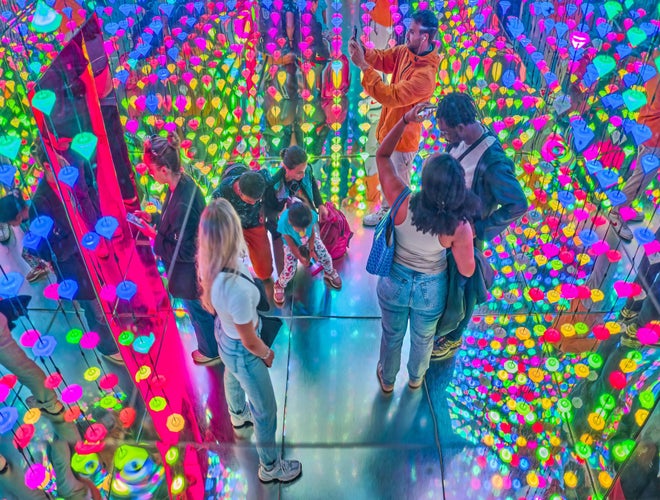 Visitors exploring a colorful, mirrored light installation at the Moco Museum in Amsterdam..jpg