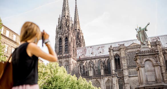 Photo of woman enjoying morning view on the famous cathedral in Clermont-Ferrand city in France.