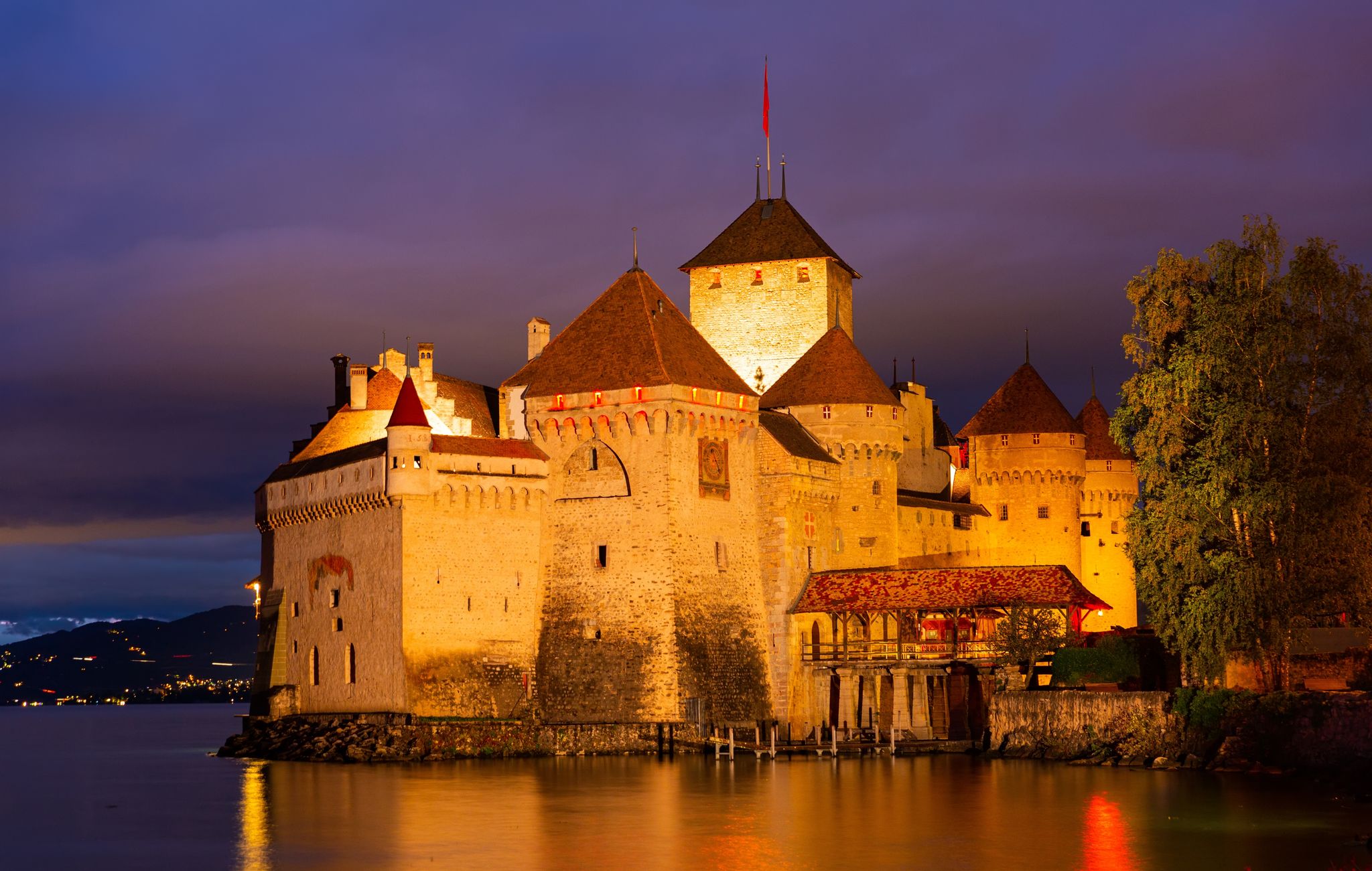 Photo of scenic view of architectural complex of fortified Chillon Castle on Lake Geneva at summer dusk, Switzerland.