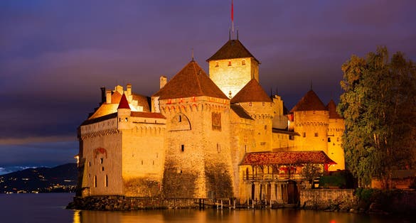 Photo of scenic view of architectural complex of fortified Chillon Castle on Lake Geneva at summer dusk, Switzerland.