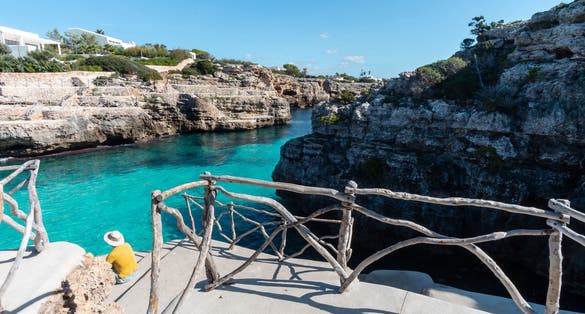 photo of a man with a perspective view at turquoise waters of Cala en Brut, Menorca beach, Balearic Islands, Spain.