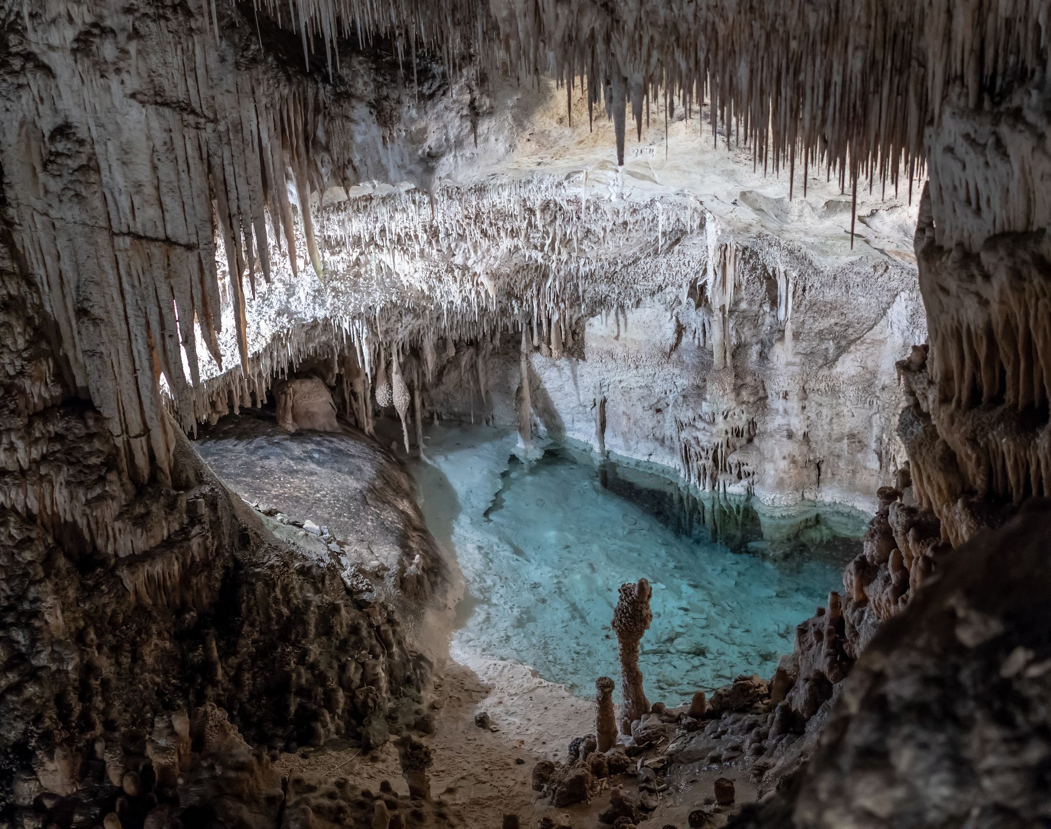 Beautiful cave interior water cavern with ancient stalactites and stalagmites