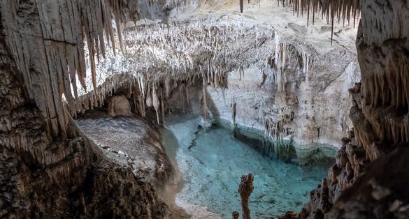 Beautiful cave interior water cavern with ancient stalactites and stalagmites