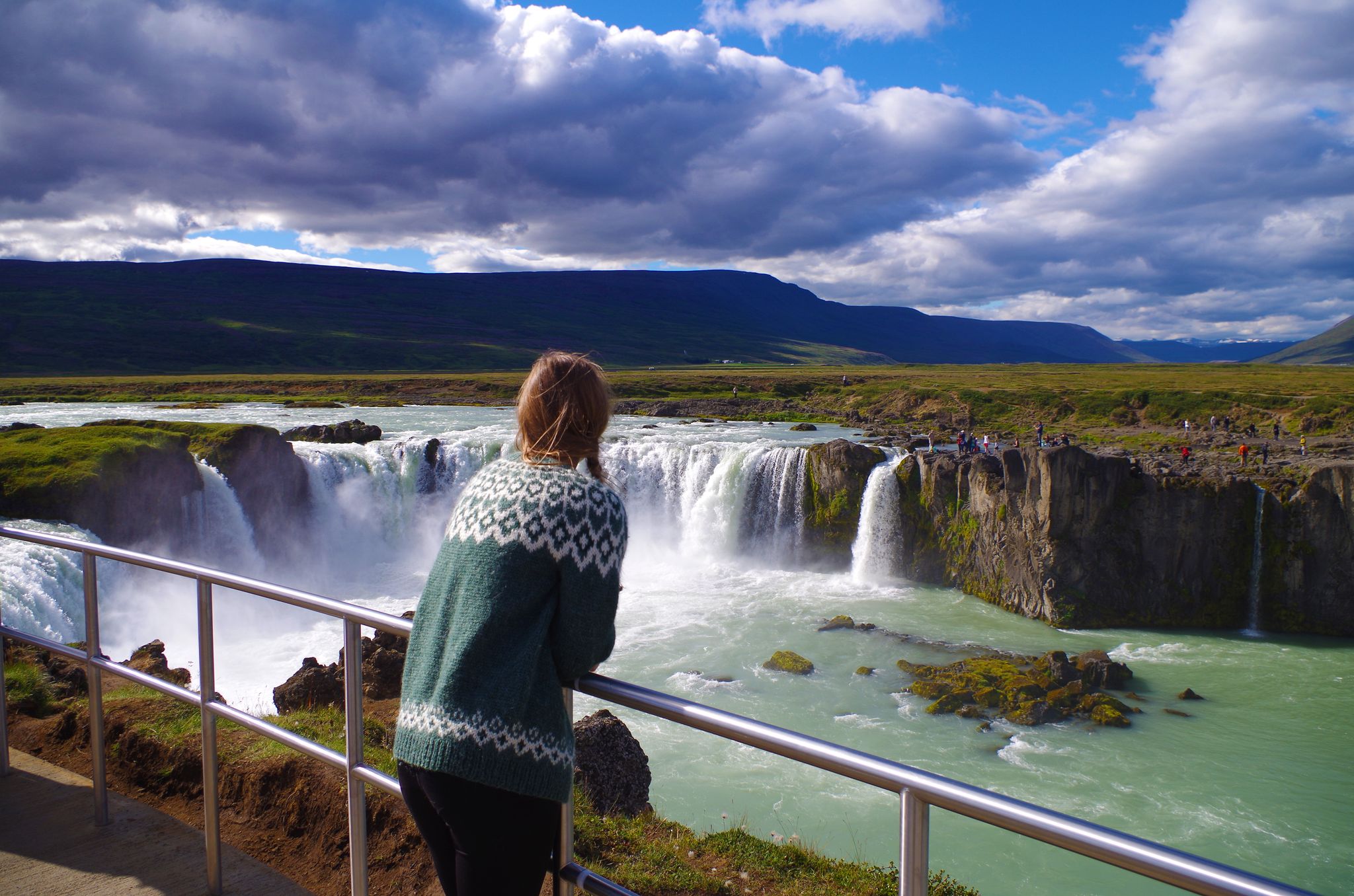 photo of Girl wearing Icelandic sweater at the Goðafoss waterfall in Iceland.