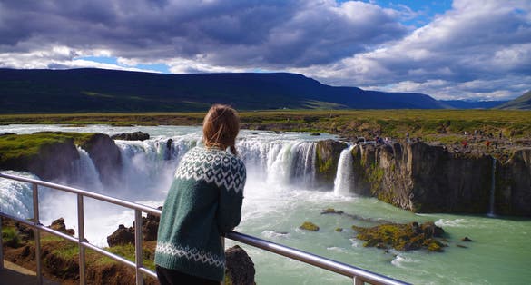 photo of Girl wearing Icelandic sweater at the Goðafoss waterfall in Iceland.