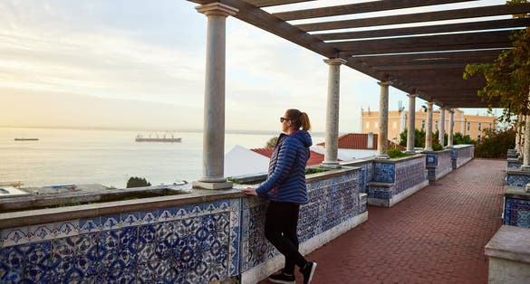 Photo of beautiful women tourist looks at the red roofs of Lisbon Portugal from the viewpoint Miradouro de Santa Luzia.