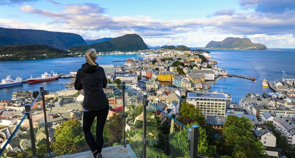 Blond woman enjoying aerial view of the colorful town of Alesund, Norway.