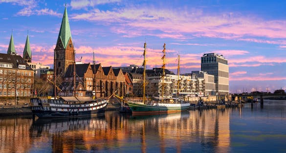 Photo of In der DÃ¤mmerung liegen Dreimaster vor der Promenade an der Weser in Bremen.