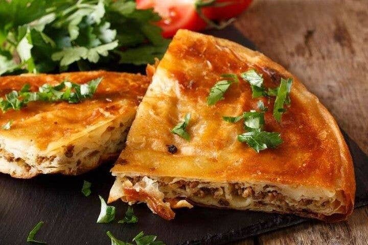 A close-up of crispy, golden-brown burek with meat, garnished with parsley, served in North Macedonia..jpg