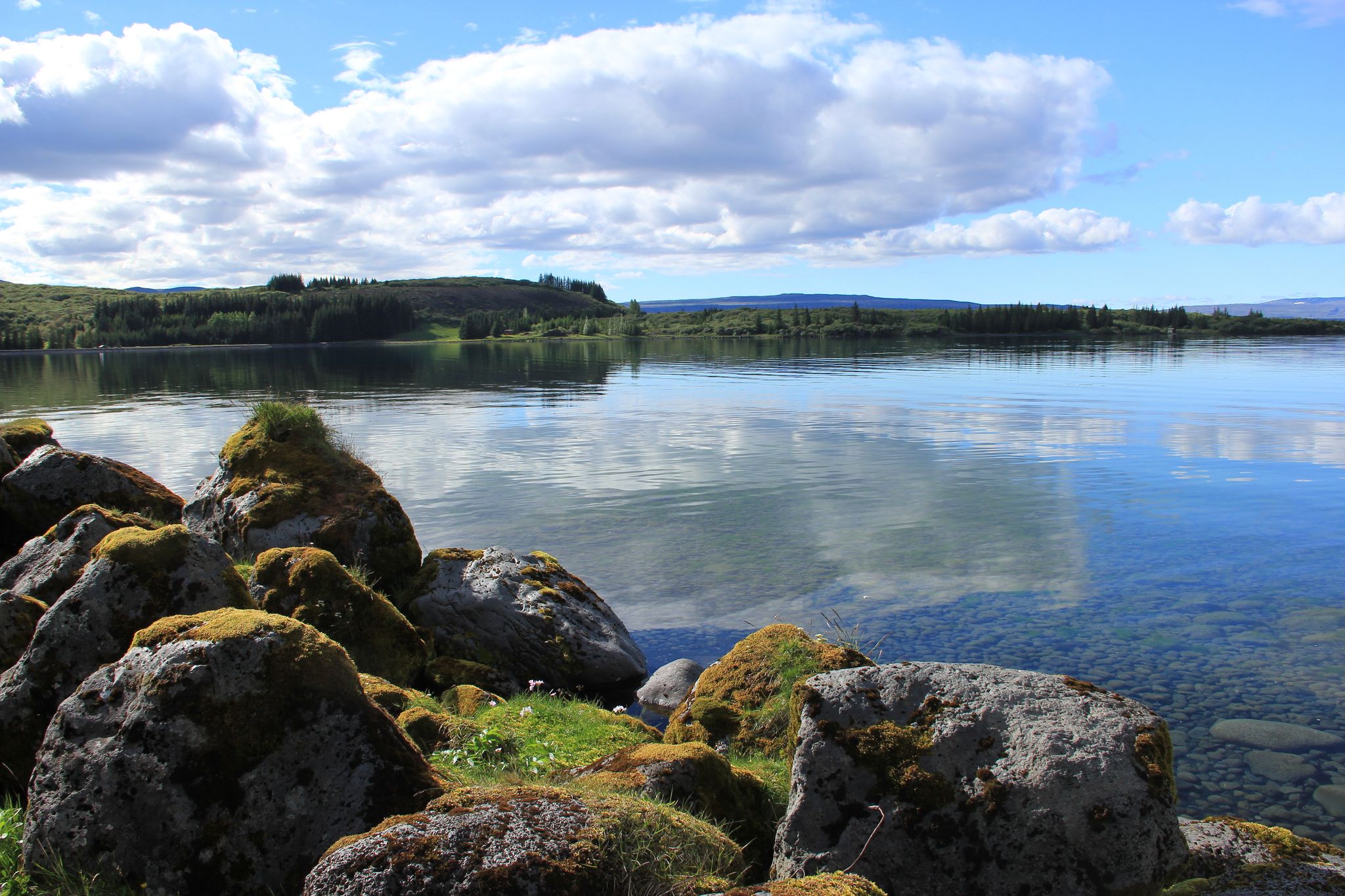 photo of Lake Þingvallavatn at Iceland with ice cold crystal water and fantastic view on clouds at sky and water surface from the rocks with grass.