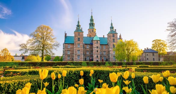 Photo of Rosenborg Castle Gardens in Copenhagen, Denmark with blue sky.