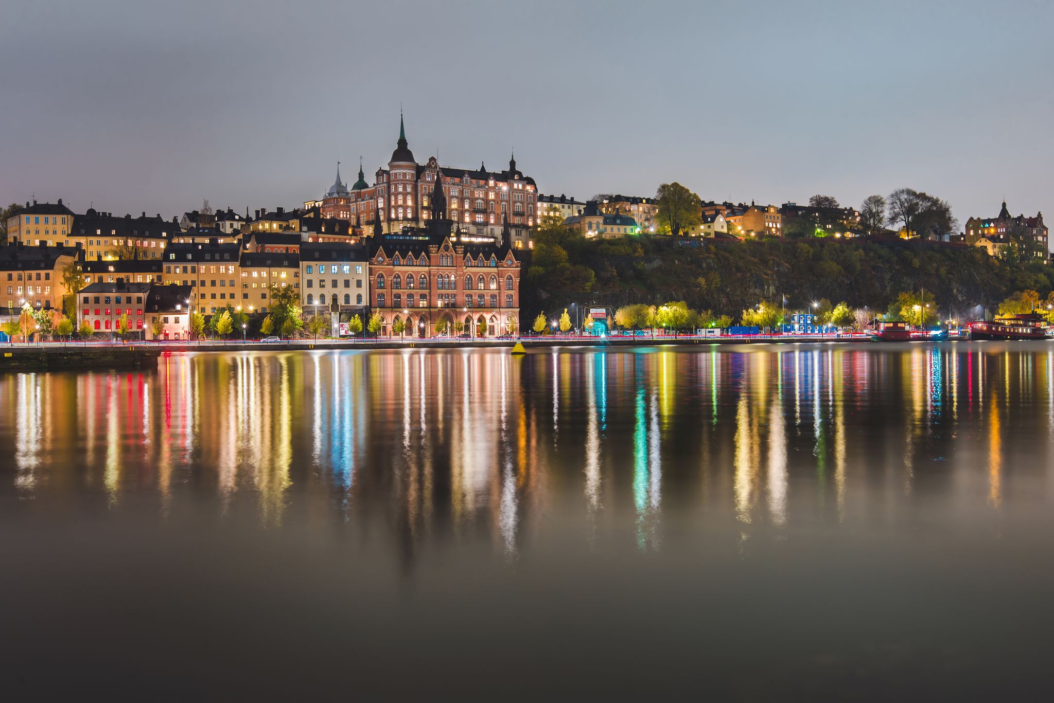 photo of Stockholm city lights and night view of Mariaberget and Sodermalm district buildings reflected in the water in Sweden.