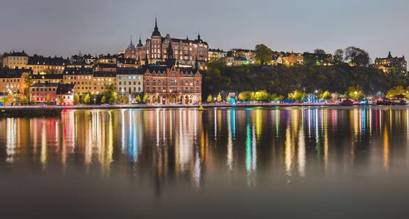 photo of Stockholm city lights and night view of Mariaberget and Sodermalm district buildings reflected in the water in Sweden.