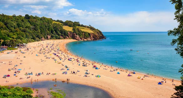 Photo of aerial view of sunny seascape with people enjoying the beach in Blackpool Sands, Devon, UK.