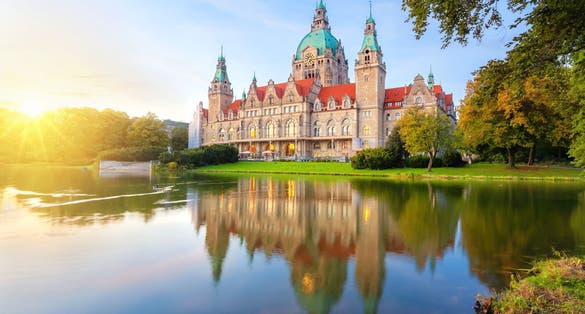 Photo of Hanover, Germany. Building of New Town Hall reflecting in water on sunset.
