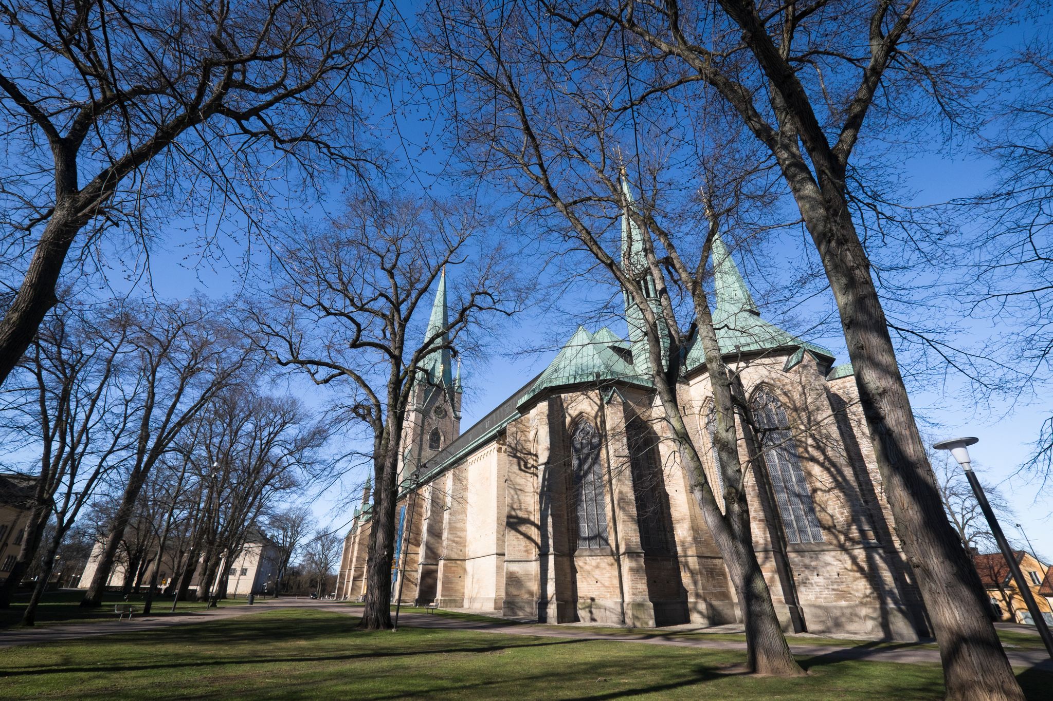 photo of back view of Linköping Cathedral with blue sky and trees in Östergötland County, Sweden.