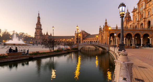 Photo of scenic view of Plaza de EspaÃ±a The Plaza de EspaÃ±a is a plaza in the Parque de MarÃ­a Luisa, Historical landmark in Seville sunset, Spain .