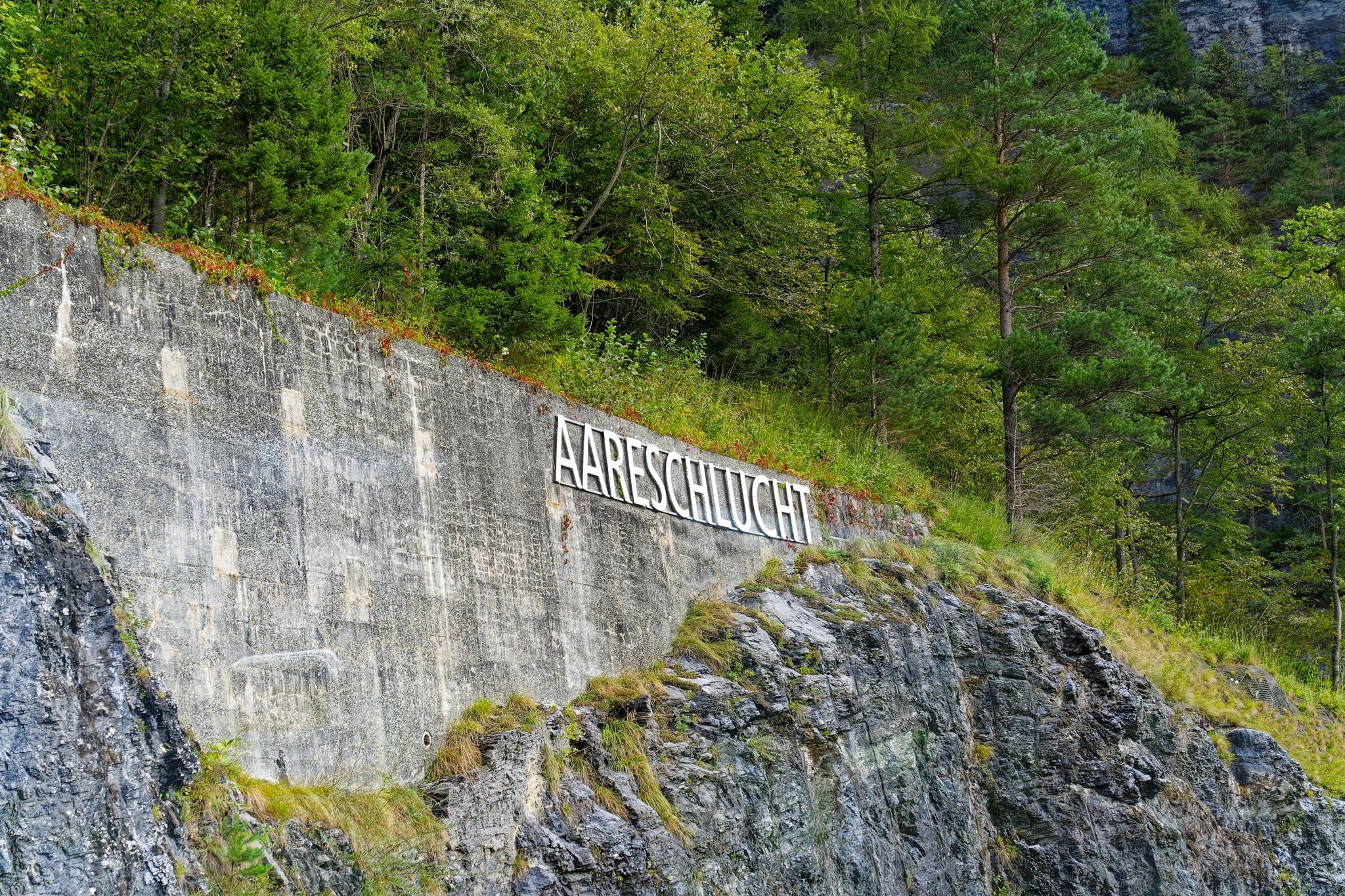photo of lettering Aare Gorge at entrance of Landmark on a cloudy late summer day in Meiringen, Switzerland.