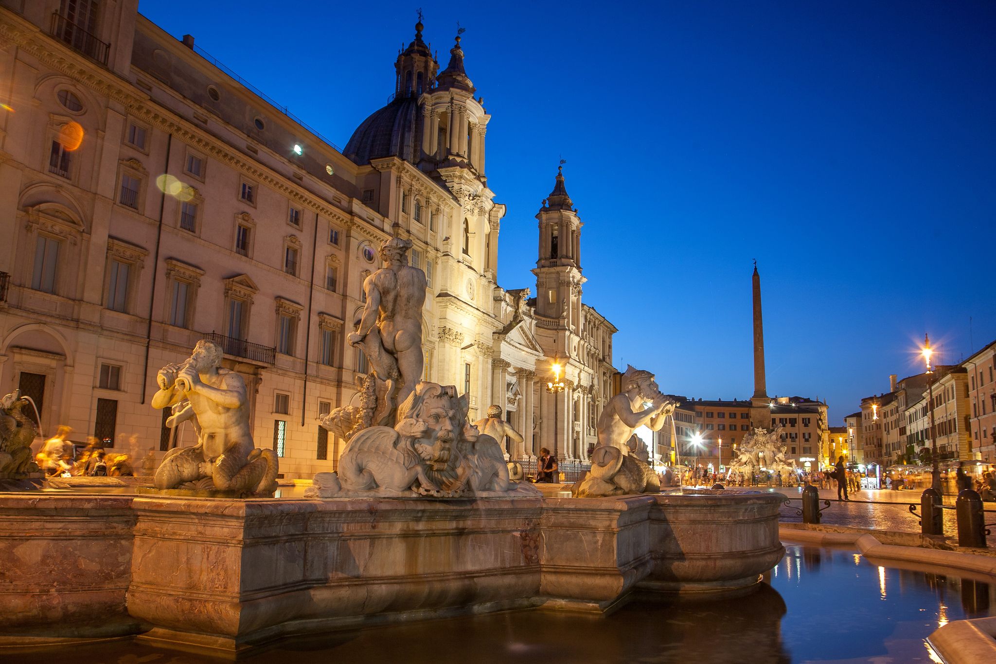 photo of illuminated at night the fontana del moro (the moor fountain) on piazza navona on the sant'Agnese in agone church background, Rome, Italy.