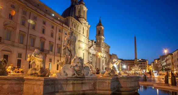 photo of illuminated at night the fontana del moro (the moor fountain) on piazza navona on the sant'Agnese in agone church background, Rome, Italy.