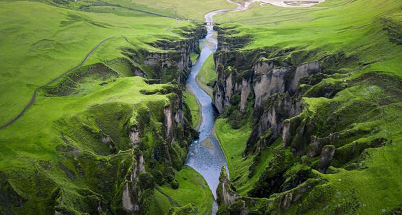 photo of unique rugged landscape of Fjaðrárgljúfur canyon covered by beautiful green moss, located in southern Iceland. Aerial shot.