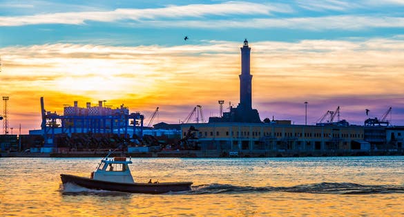 photo of sunset at Genoa's port, silhouette of the Lanterna: the main lighthouse and symbol of the city, in Italy.