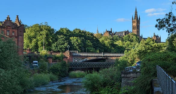 photo of view of View of Glasgow University, Glasgow, Scotland. In the image you can see the bridge over the river, the greenery of the trees and the beautiful tower of the university.
