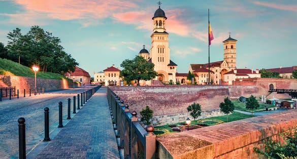 photo of view of Colorful cityscape of Fortified churches inside Alba Carolina Fortress. Great sunset in Transylvania, Alba Iulia city, Romania, Europe. Traveling concept background.