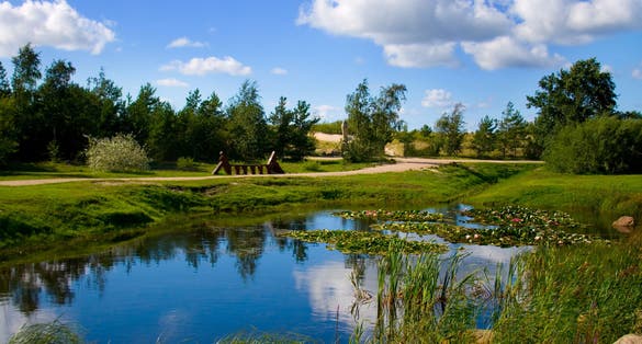 Photo of beautiful nature park on a summer day in city of Ventspils, Latvia. This is a clean and green park with a small lake inside of it. Clouds, sun and silence it-s a good atmosphere for relaxation.