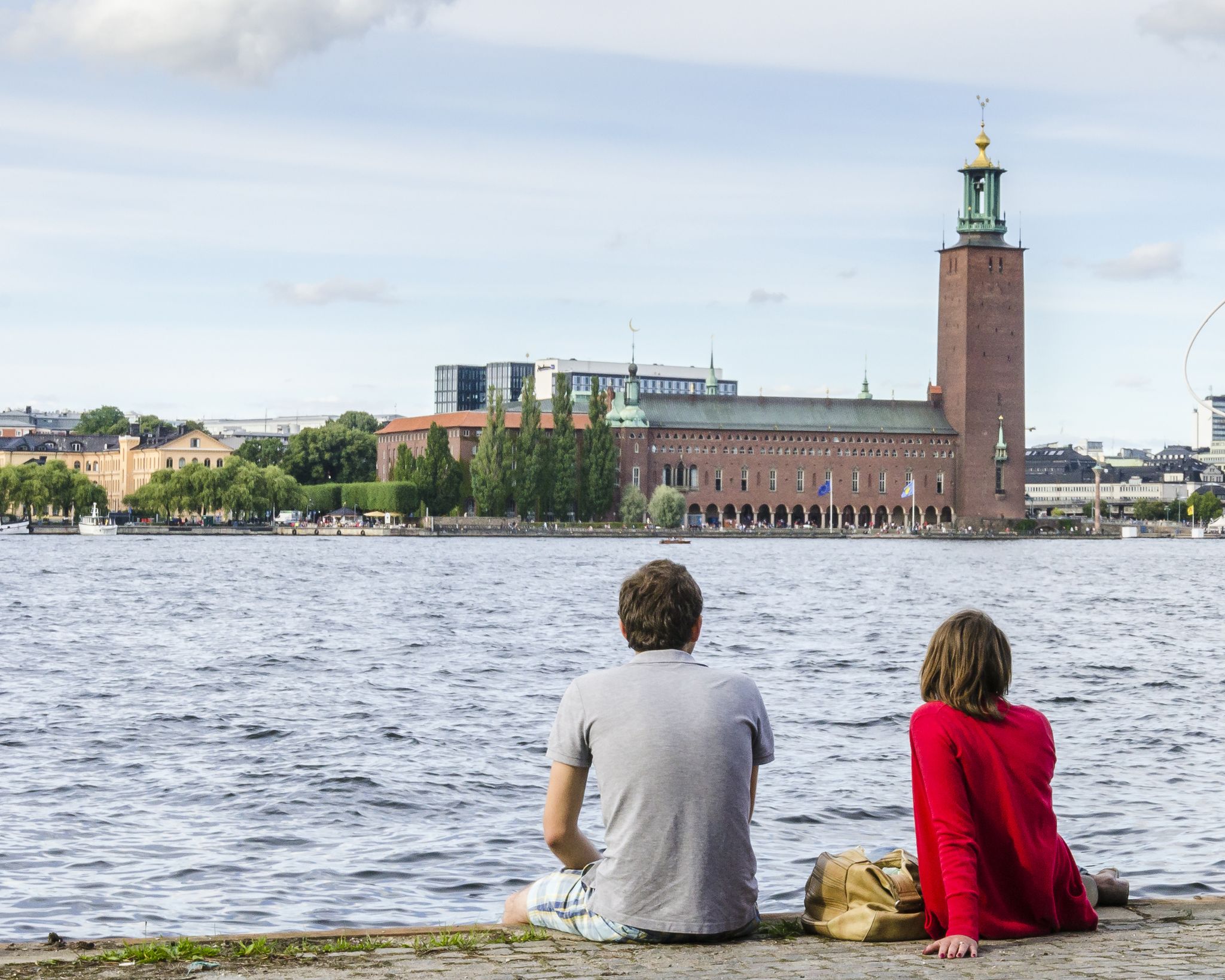 photo of man with a girl opposite the Stockholm City Hall (Stadshuset) in Stockholm, Sweden.