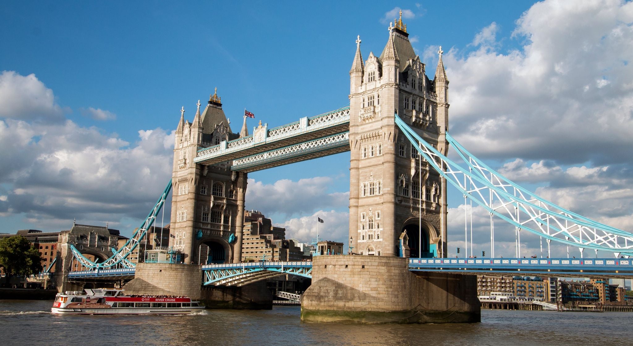 Tower Bridge in London with a river cruise boat passing underneath on a sunny July day..jpg