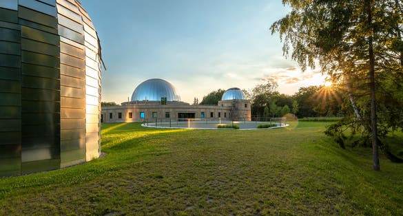 photo of Sunset at the Silesian Planetarium. Reflecting the sky and sunbeams of the planetarium and observatory domes. Aluminum panels on the roof. Chorzow, Silesian Park, Poland.