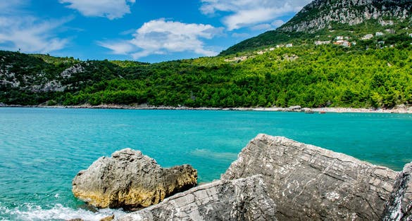 Photo of Montenegro coast seascape with perfect blue water with mountains around, blue sky near Bar town.
