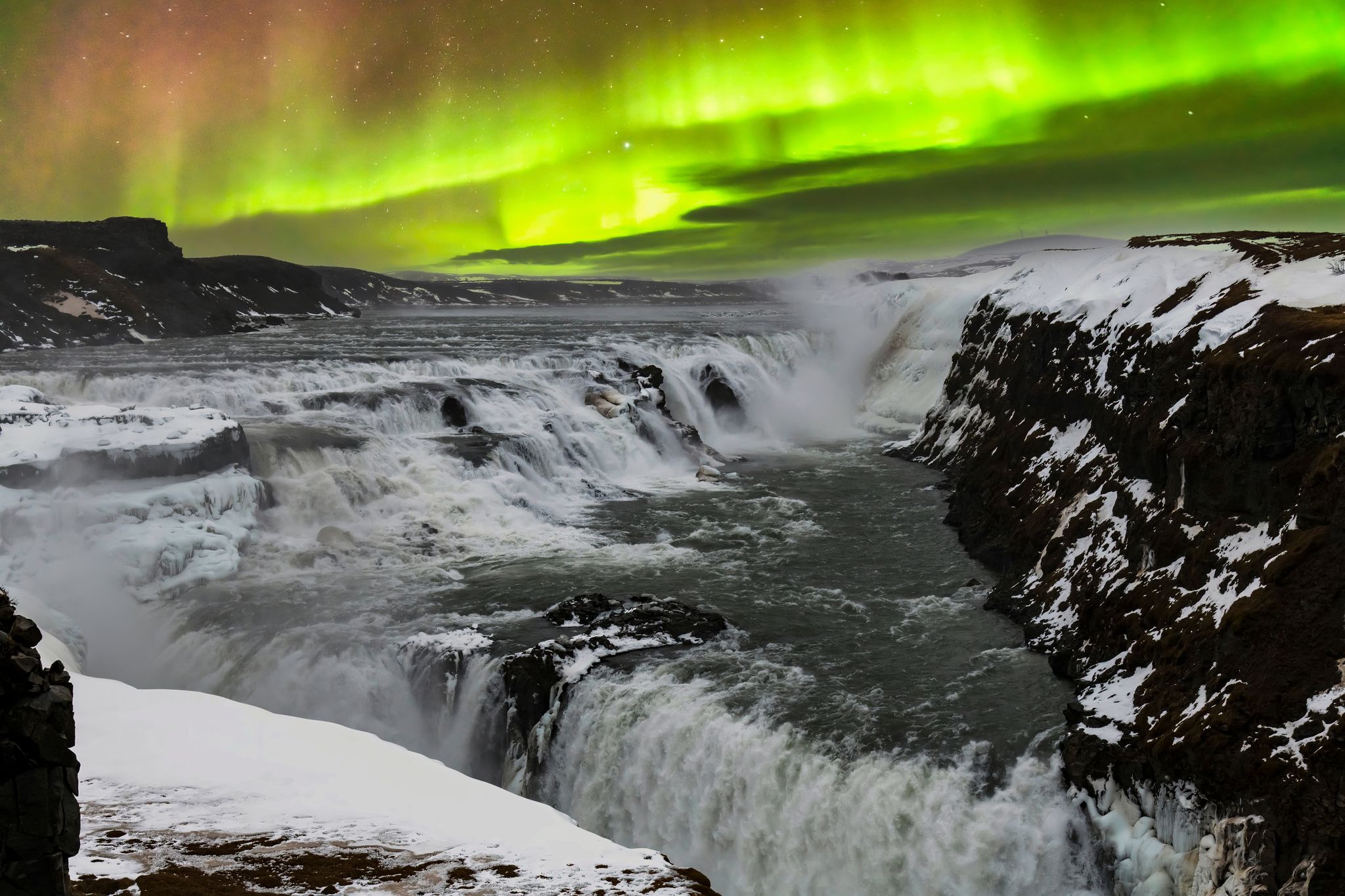 photo of panoramic view during aurora borealis or northern lights over the gullfoss waterfall in the hvita river flowing from hvitarvatn lake and the langjokull glacier in Iceland.
