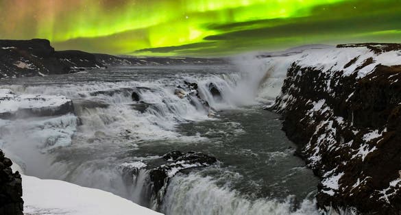 photo of panoramic view during aurora borealis or northern lights over the gullfoss waterfall in the hvita river flowing from hvitarvatn lake and the langjokull glacier in Iceland.