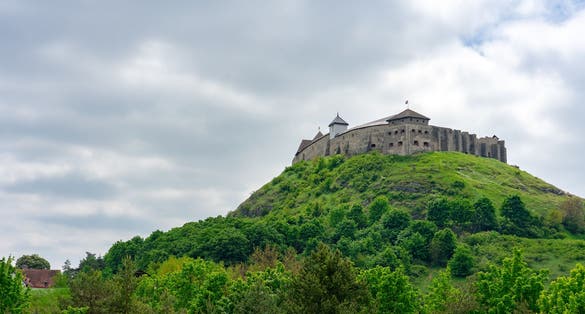 Photo of Sümeg castle on the hill in Hungary spring time with green trees .