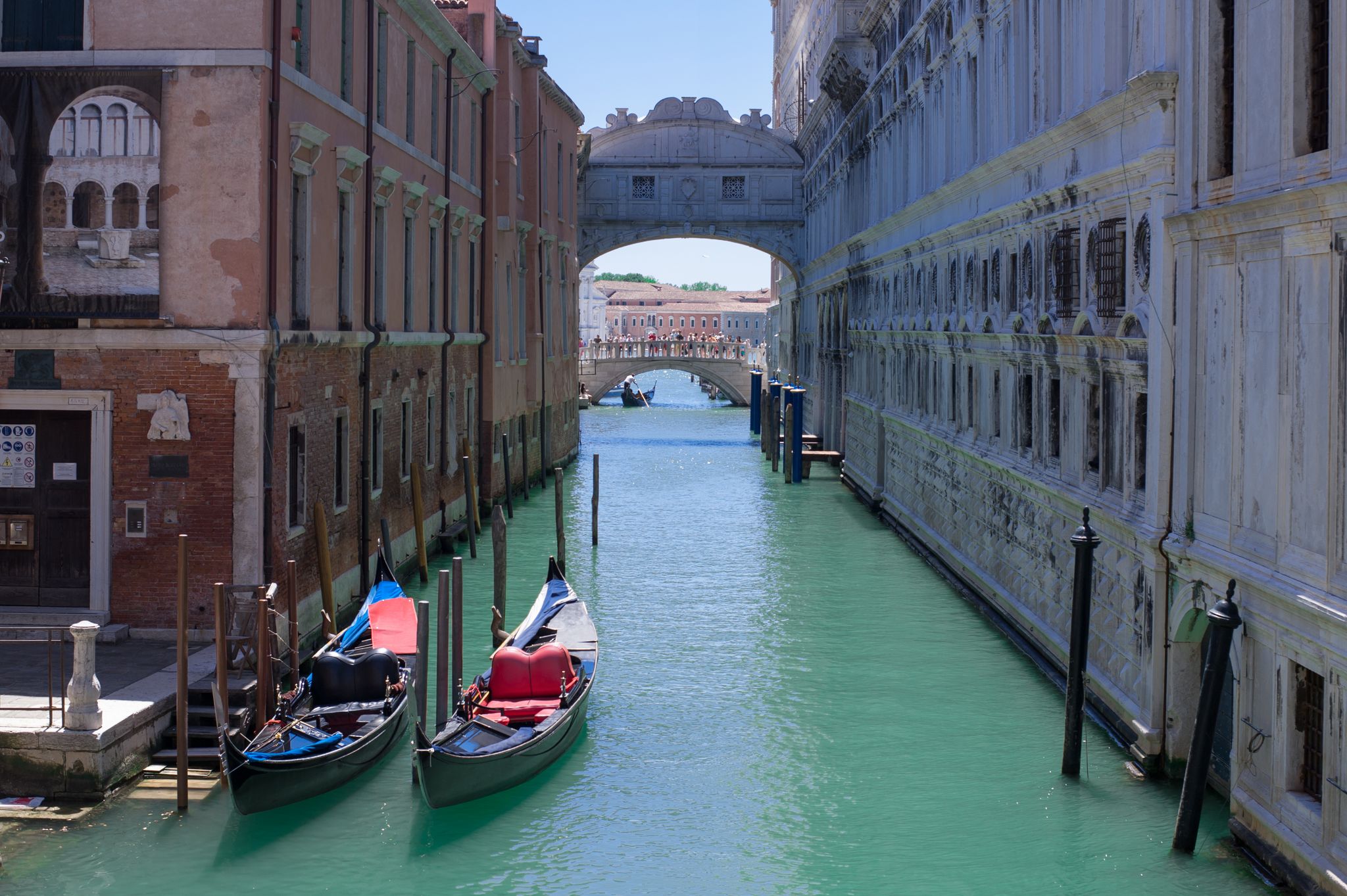 photo of romantic idyllic view of gondolas moored in narrow canal by renaissance facade of Doge's Palace and Ponte de i Sospiri .