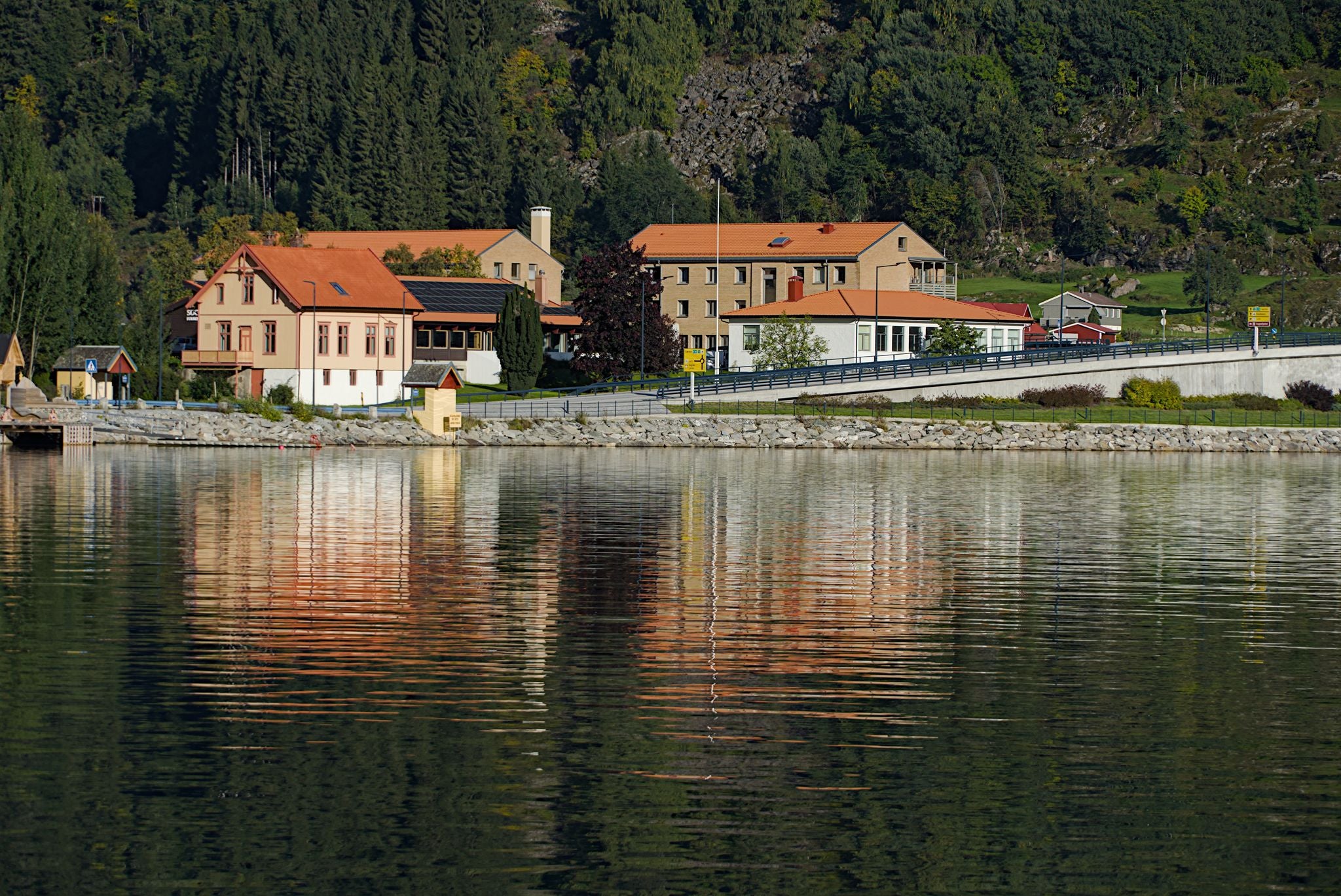 photo of view of Colorful buildings along the hill side and their reflections on the lake in Sogndal, Norway.