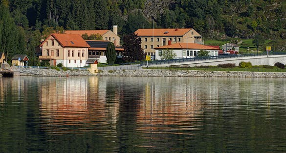 photo of view of Colorful buildings along the hill side and their reflections on the lake in Sogndal, Norway.