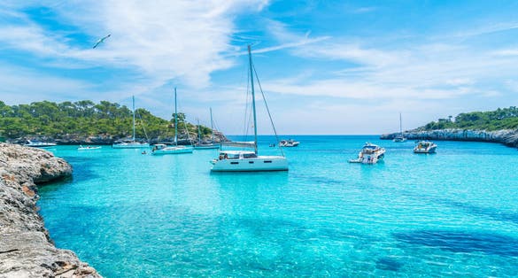 Photo of landscape with boats and beautiful turquoise sea water on Cala Mondrago, Majorca island, Spain.