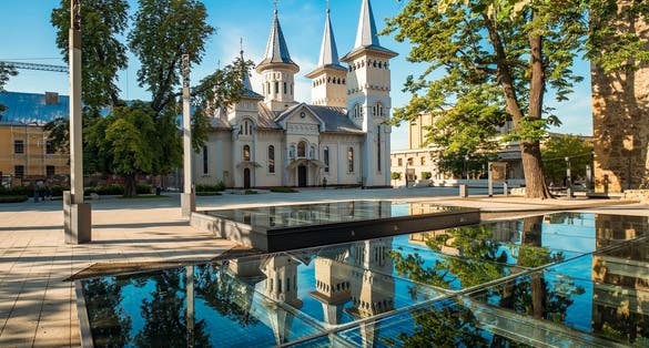 Central square of Baia Mare, the capital of Maramures County, Romania with Saint Nicholas Orthodox Church reflected in the glass