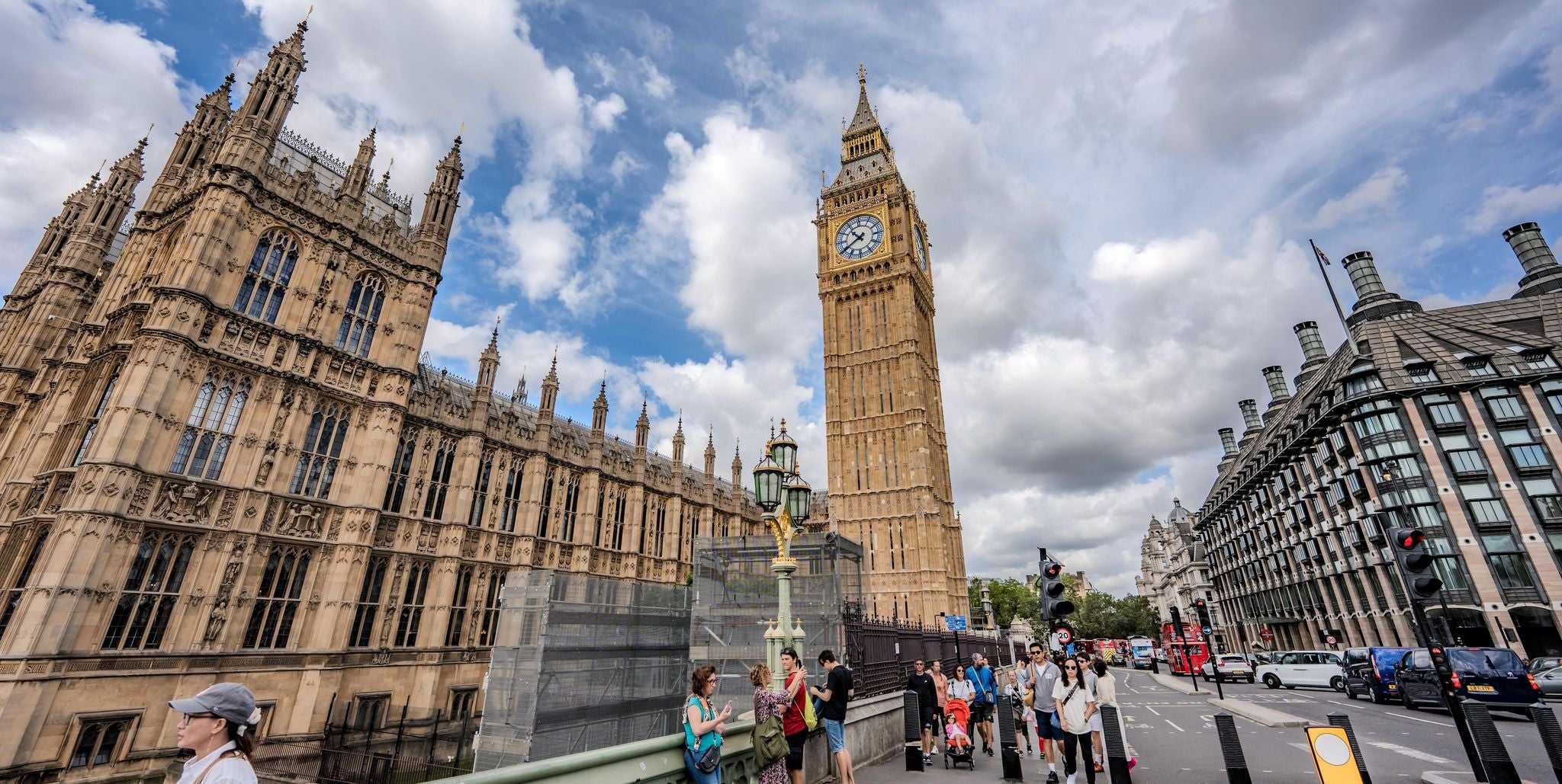 Tourists walk near Big Ben and the Houses of Parliament under partly cloudy skies in London in July..jpg