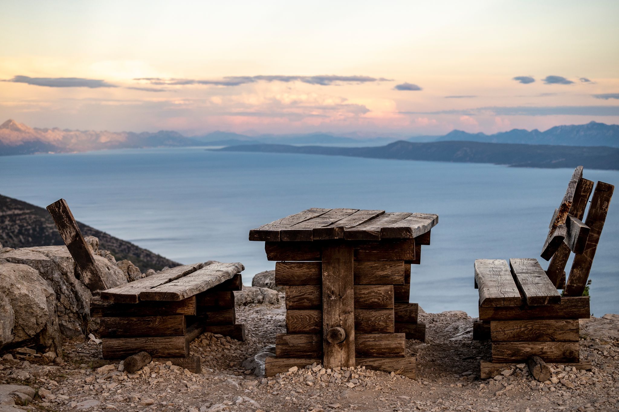Photo of wooden table and bench on Vidova Gora, highest peak on Brac island, Croatia, overlooking adjacent archipelago and islands of Croatian sea.
