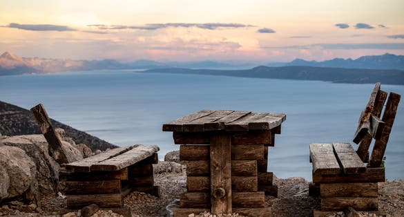 Photo of wooden table and bench on Vidova Gora, highest peak on Brac island, Croatia, overlooking adjacent archipelago and islands of Croatian sea.