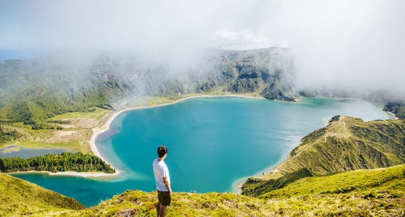 Photo of tourist looking at beautiful Lagoa do Fogo lake in Sao Miguel Island, Azores, Portugal. 