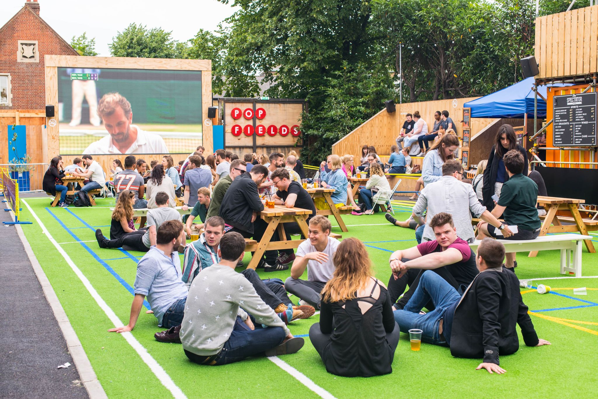 People relaxing and watching Wimbledon at a lively outdoor screening area in London during summer..jpg