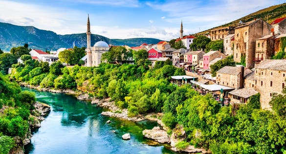 Mostar, Bosnia and Herzegovina. Morning sun on Nerteva River and Old City of Mostar, with Ottoman Mosque.