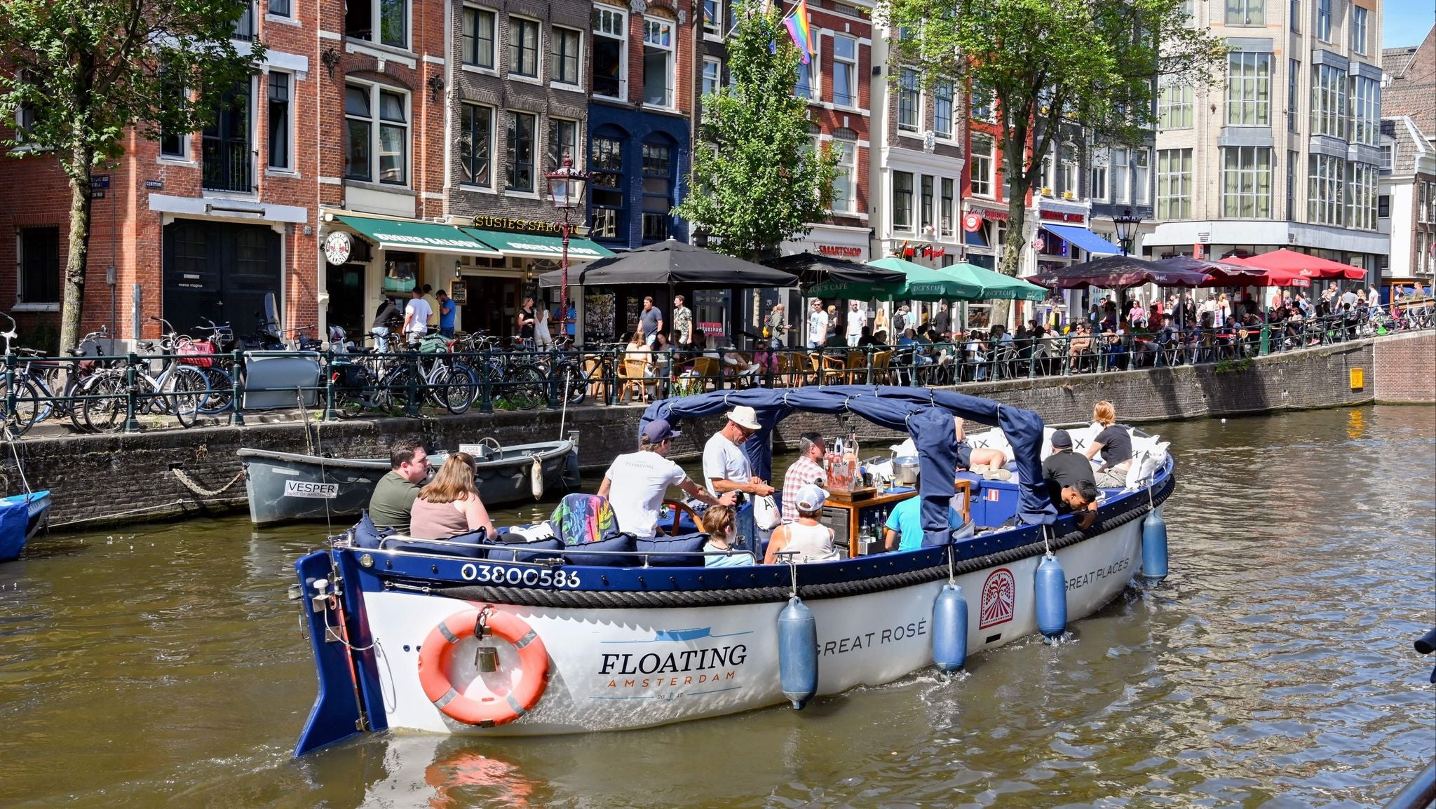Tourists enjoying a summer canal cruise past cafés and terraces in central Amsterdam..jpg