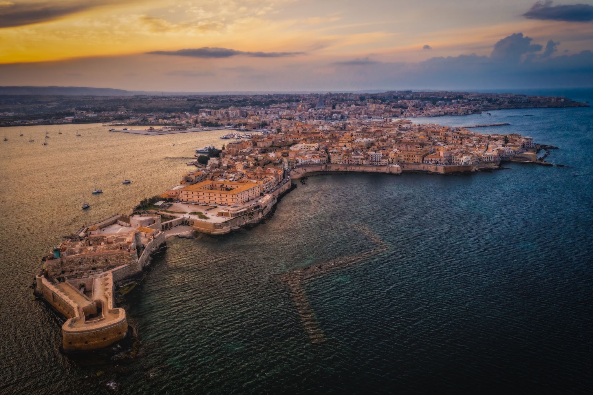 Siracusa, Ortigia Island from the air at sunset, Sicily, Italy. Isola di Ortigia, coast of Ortigia island at city of Syracuse, Sicily, Italy. Aerial view. June 2023