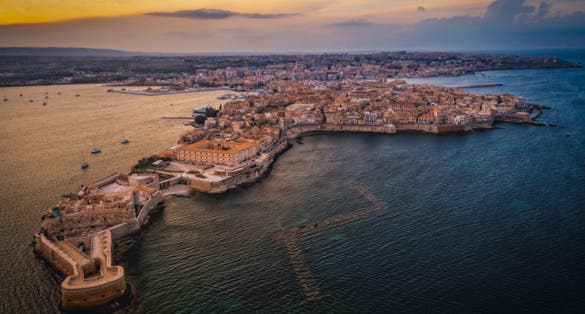 Siracusa, Ortigia Island from the air at sunset, Sicily, Italy. Isola di Ortigia, coast of Ortigia island at city of Syracuse, Sicily, Italy. Aerial view. June 2023
